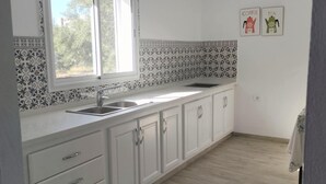 A modern kitchen with white cabinets, a large window, and a pendant light. - Quiet house with garden Pets welcome (Sakiet Ezzit)