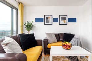 Uma sala de estar moderna com um sofá, uma mesa de centro com frutas e uma planta.