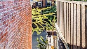 A narrow outdoor stairway with a wooden handrail, flanked by brick walls and a wooden fence. - Amazing West End apartment walkable to downtown and the waterfront. (Portland)