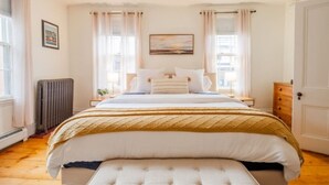 A bedroom with a large bed, a bedside table, a radiator, and a door. - Amazing West End apartment walkable to downtown and the waterfront. (Portland)