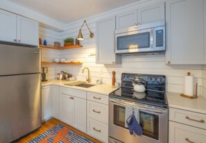 A kitchen with white cabinets, a stainless steel refrigerator, a microwave, an oven, and a sink. - Amazing West End apartment walkable to downtown and the waterfront. (Portland)
