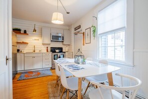 A modern kitchen with white cabinets, a dining table with chairs, and a large window. - Amazing West End apartment walkable to downtown and the waterfront. (Portland)