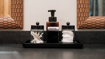 A bathroom vanity with a soap dispenser, a container of cotton swabs, and a jar of hand soap.