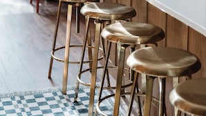 A wooden interior with a long dining table, red chairs, and a bar area with stools.