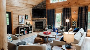 A cozy cabin interior with a fireplace, wooden walls, a sofa, and a coffee table.