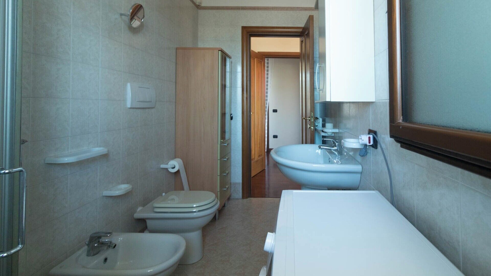 Une petite salle de bain comprenant des toilettes, un bidet, un lavabo et une douchette pour bidet.