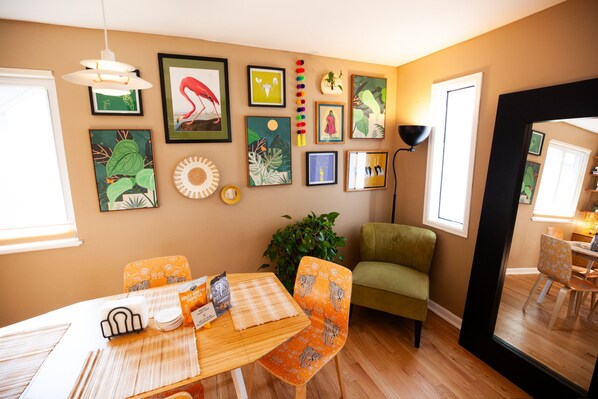 Un comedor con una mesa de madera, sillas estampadas color naranja y un sofá verde.