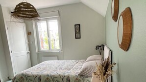 A bedroom with a bed, a bedside table, a hanging light fixture, a window, and a door. - A unique stay in an old railway station, in the heart of the Cotentin sea & countryside. (Saint-Georges-de-la-Rivière)