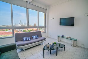 A modern living room with a large window, a sofa, a coffee table, a TV, and a glass shelf. - Charming 1-bedroom apartment with AC, WiFi in beautiful Cartagena de Indias (Cartagena de Indias)
