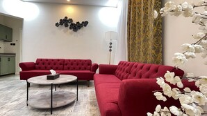 Un salon moderne avec un ensemble de canapés rouges, une table basse ronde et un élément décoratif mural.
