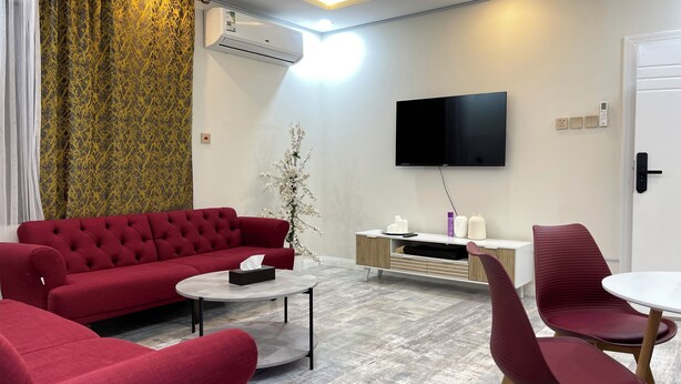 Un salon moderne avec un canapé rouge, une table basse et un téléviseur fixé au mur.