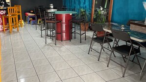 A salon with a blue wall, tiled floor, and multiple chairs and tables. - La casona rio 2  (Río Segundo)