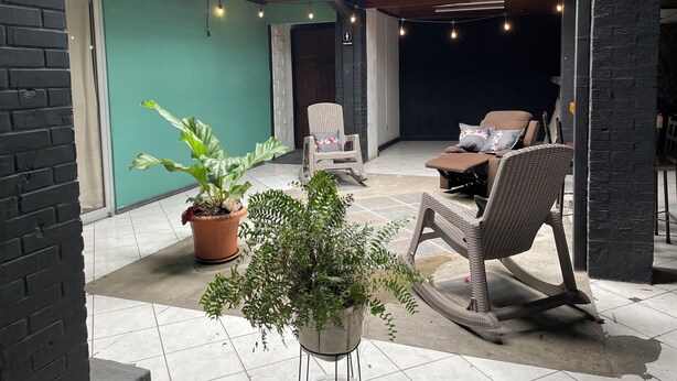 A covered patio area with wicker furniture, potted plants, and a view of the interior through a glass ceiling. - La casona rio 2  (Río Segundo)