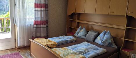 Un dormitorio con cama de madera, cortina a rayas rojas y blancas, y un armario de madera.
