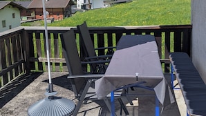 Una terrazza con tavolo e sedie, un ombrellone e vista su un paesaggio montuoso.