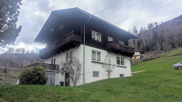 Una casa a due piani con tetto spiovente, balconi in legno e un garage.