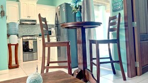 Una cocina con armarios blancos, un refrigerador, una estufa y una mesa de comedor con sillas.