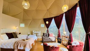 A tented accommodation with a bed, a sofa, a table, and a chair. - Monteverde Rainforest Domes (Monteverde)