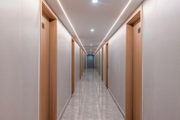 A long, narrow hallway with wooden doors on both sides, leading to a distant end. - Huayi Hotel (Shanghai)