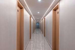 A long, narrow hallway with wooden doors on both sides, leading to a distant end. - Huayi Hotel (Shanghai)
