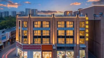 A multi-story hotel with a brick facade, large windows, and a storefront at the ground level.