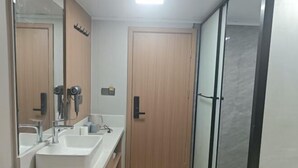 A bathroom with two sinks, a mirror, and a shower area. - Huayi Hotel (Shanghai)