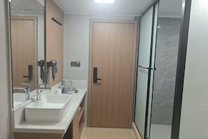 A bathroom with two sinks, a mirror, and a shower area. - Huayi Hotel (Shanghai)