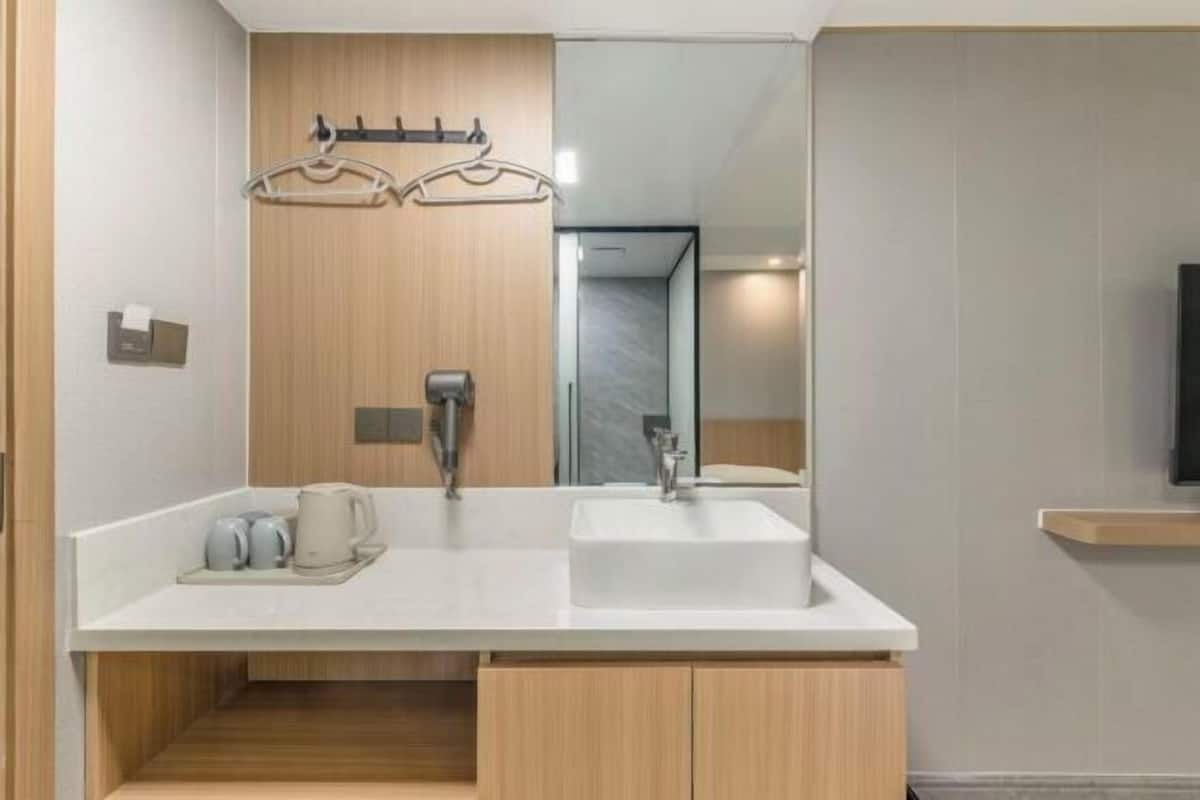 A modern bathroom with a white sink, wooden cabinets, a towel rack, and a mirror.