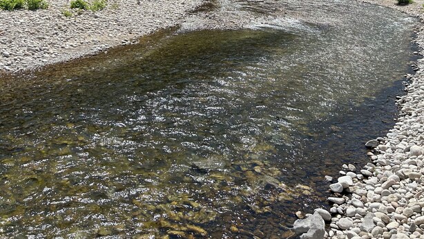 Une rivière aux eaux claires, bordée d’un paysage rocheux et d’une végétation luxuriante.