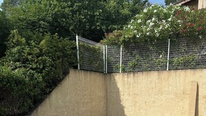 Une piscine rectangulaire à l’eau d’un bleu limpide, entourée d’une terrasse carrelée et d’un petit muret en pierre.