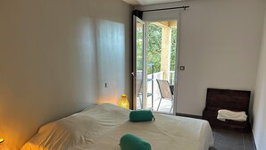 Une chambre à coucher avec un lit, une table de chevet, une lampe, une valise et une vue sur l’extérieur.