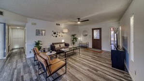 Ein geräumiges Wohnzimmer mit einem braunen Ledersofa, einem Couchtisch und einem Deckenventilator.