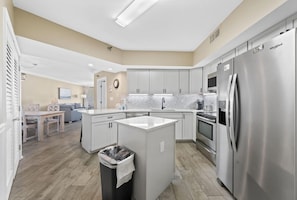 A modern kitchen with white cabinets, stainless steel appliances, and a central island.