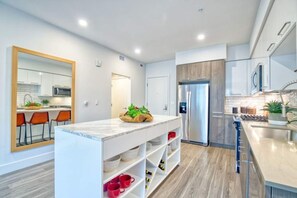 Una cocina moderna con armarios blancos, una isla de mármol y un horno empotrado.