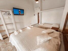 Una habitación de hotel con una cama grande, un televisor en la pared y un armario de madera.