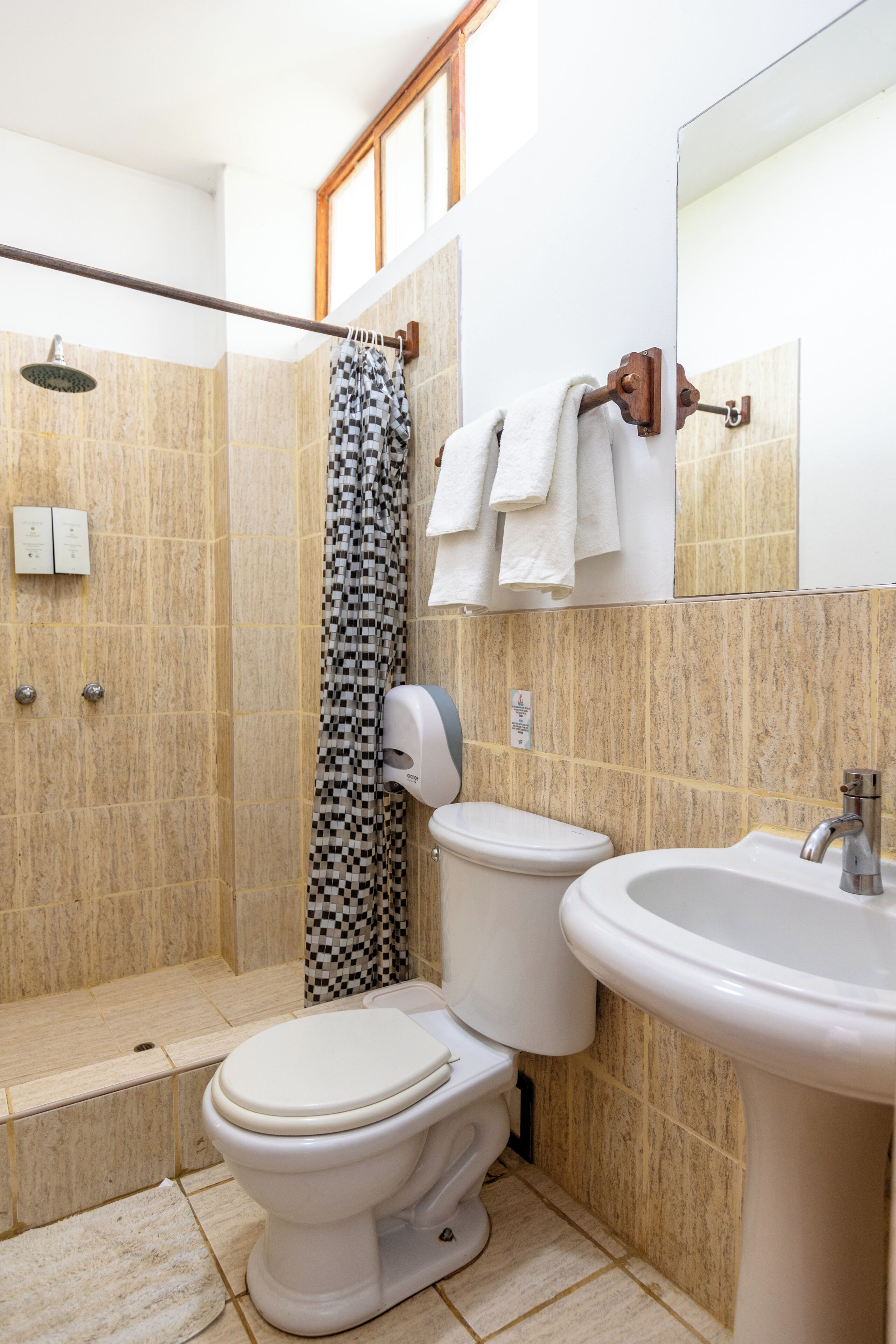 A bathroom with a shower, toilet, sink, and a towel rack.