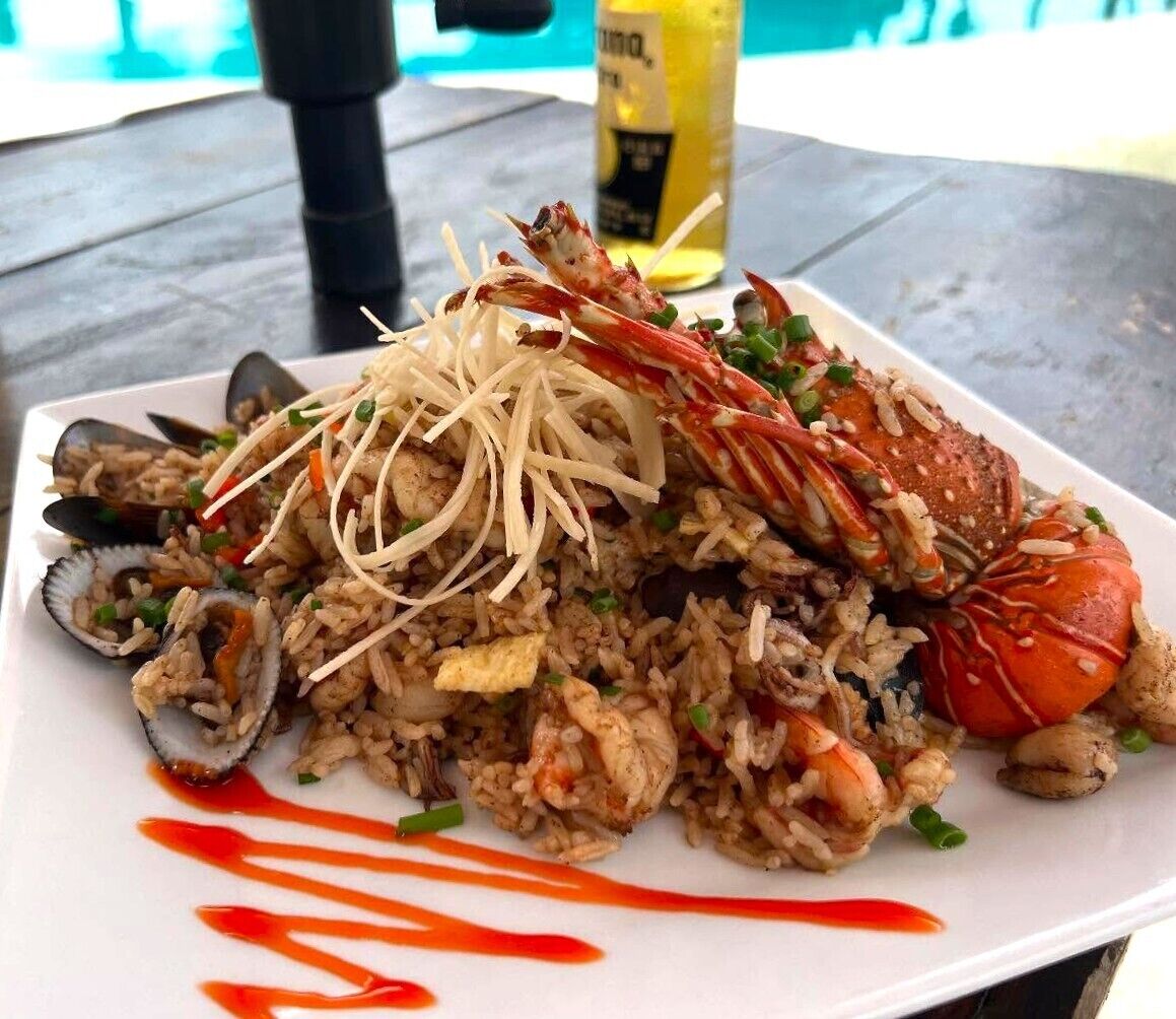 A seafood dish with rice, mussels, and lobster on a white plate.