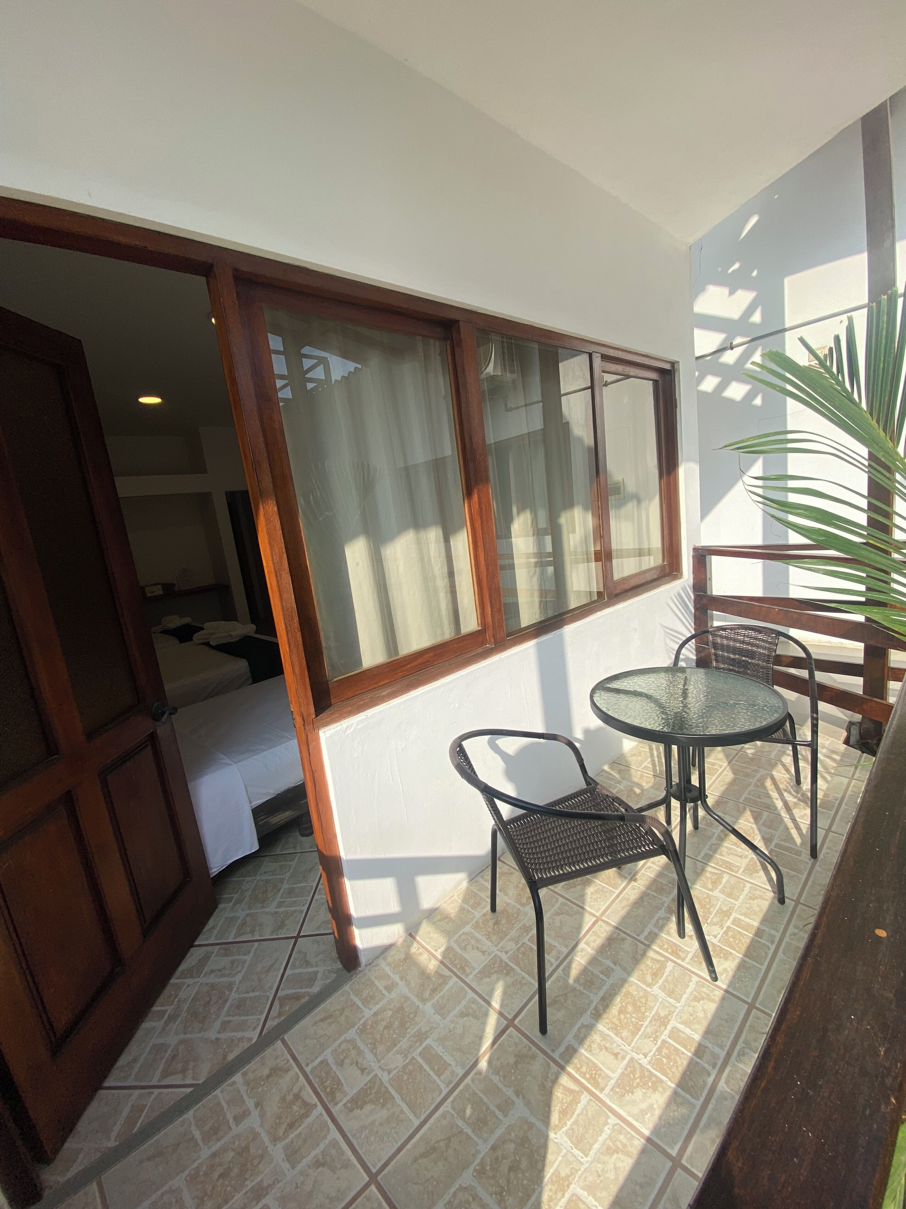 Ein Balkon mit Glastisch und Stühlen, einem Blumentopf und Blick ins Innere.