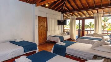 A hotel room with three single beds, a TV, and a wooden ceiling.