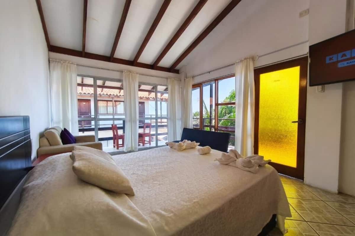 Een hotelkamer met een groot bed, een televisie, een balkon met uitzicht en een schuifdeur.