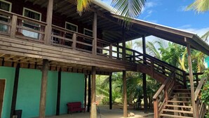 A wooden structure with a balcony and a staircase leading to a covered area.