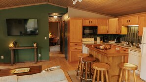 Une cuisine moderne avec des meubles en bois, un îlot central doté de tabourets, un four encastré et un four à micro-ondes.