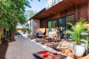 Une terrasse extérieure moderne, dotée d’une plateforme en bois, d’un espace salon et d’une grande plante en pot.