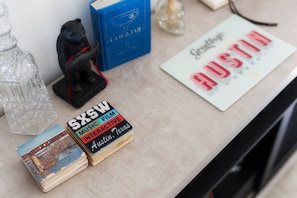 Une table avec un verre à cocktail, une figurine d’ours, un livre bleu, une carte postale et une pile de cartes postales.