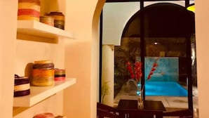 An interior view of a room with a dining area, shelves with baskets, and a view of a pool through a glass door. - Luxury Home & Pool, 5 Min from Downtown (Merida)