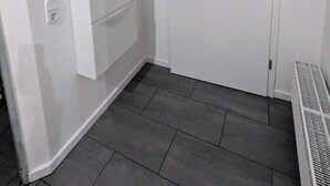 A white door with a handle, a small wooden shelf above it, and a sign on the wall to the left. - Bright, cozy vacation apartment for 3-4 people (Kalletal)