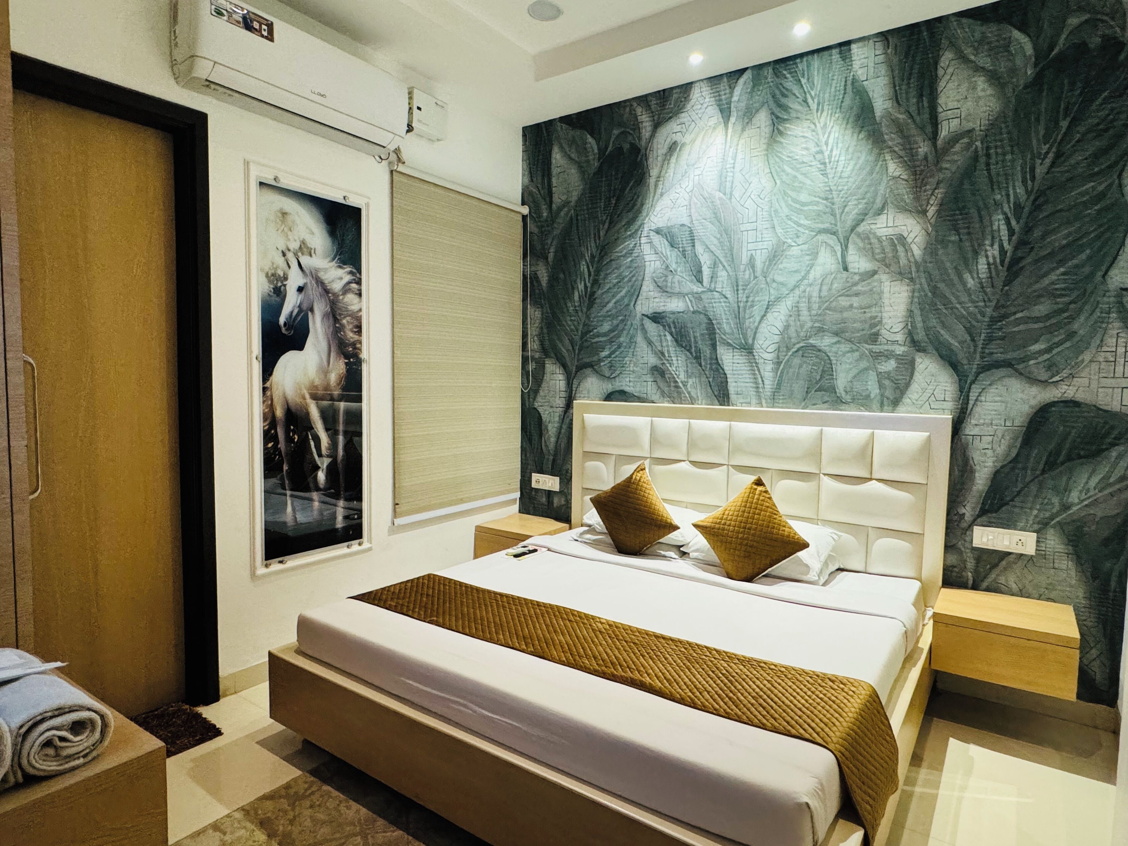 A modern hotel room with a large bed, a poster of a horse, a mural on the wall, and a wooden door.