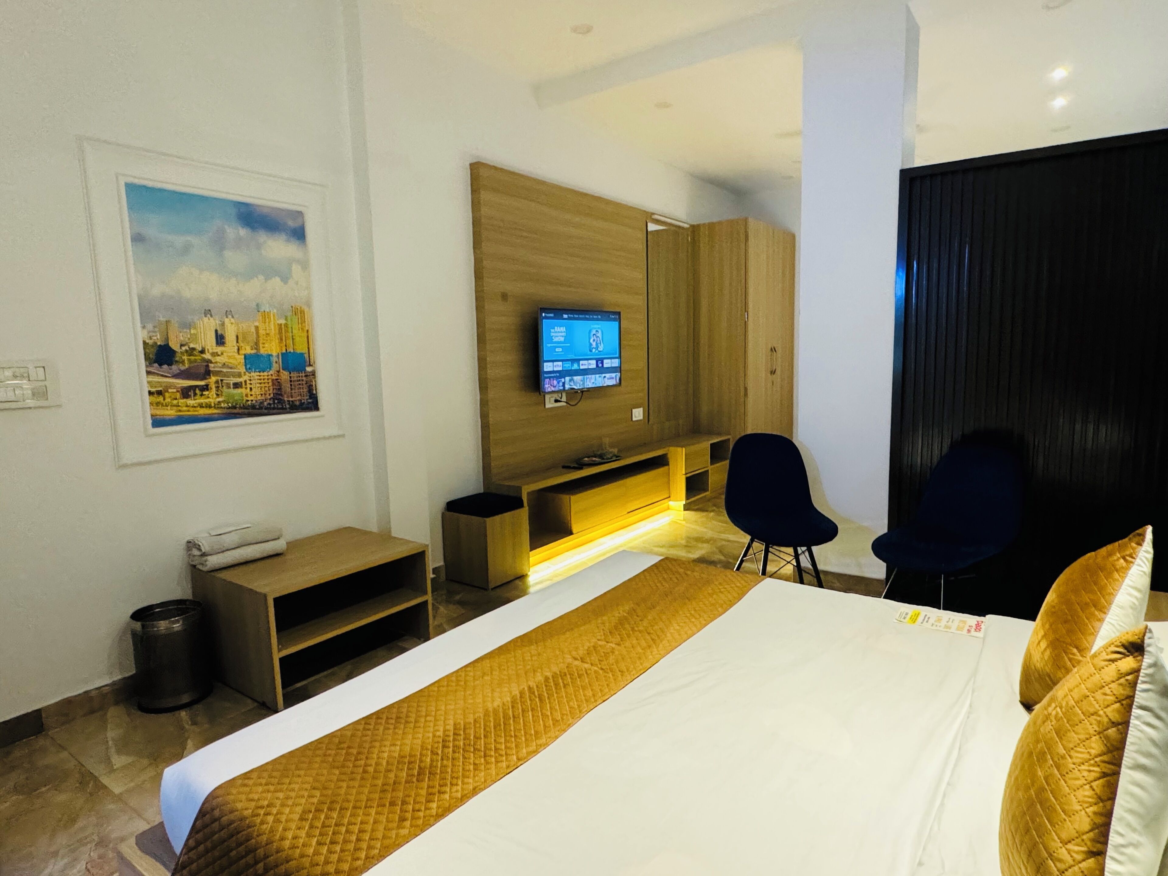 A hotel room with a bed, a TV mounted on the wall, a desk, and a chair.