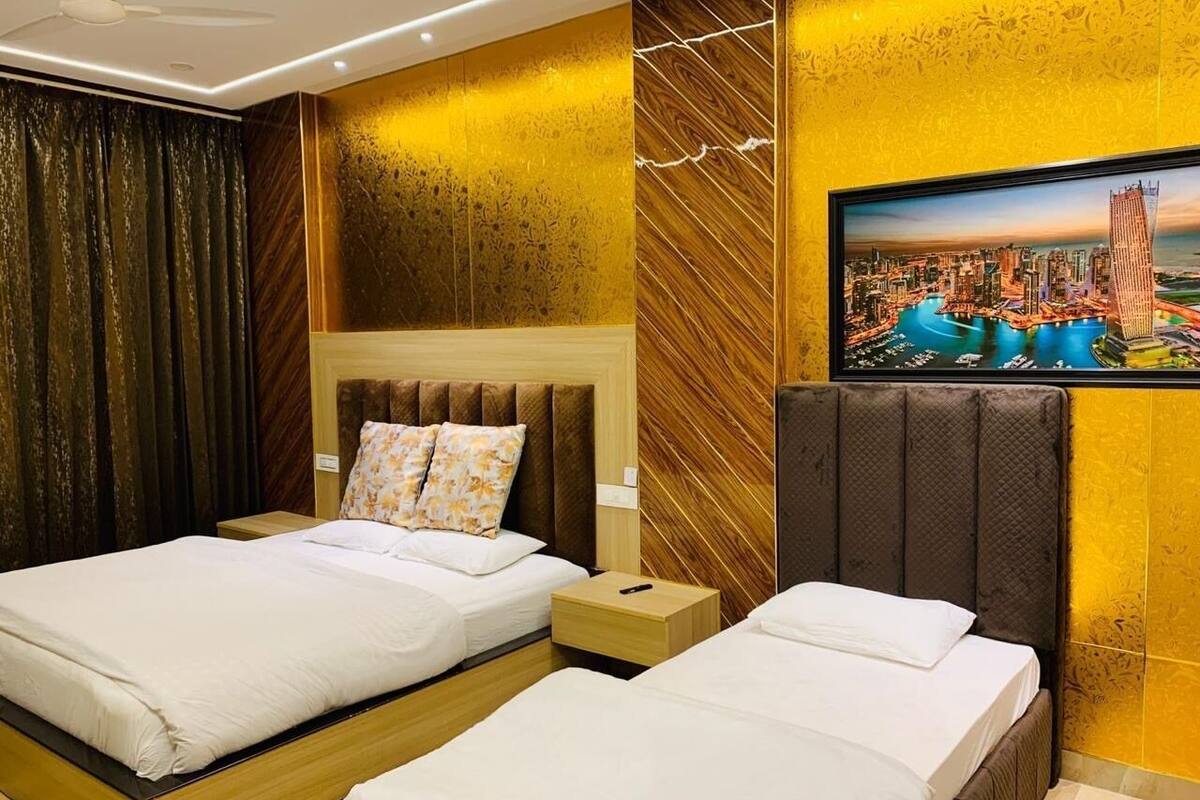 Hotelkamer met twee bedden, een groot stadsgezichtschilderij, en een modern design met houten panelen en een plafondventilator.