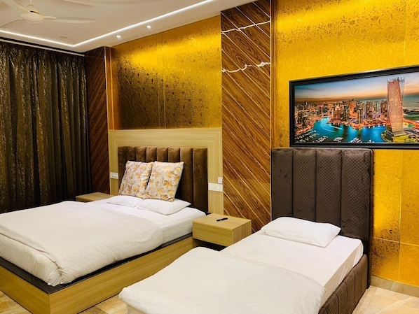 A hotel room with two beds, a large painting of a cityscape, and a modern design with wooden panels and a ceiling fan. - HolidayVilla & Suites Amritsar (Amritsar)